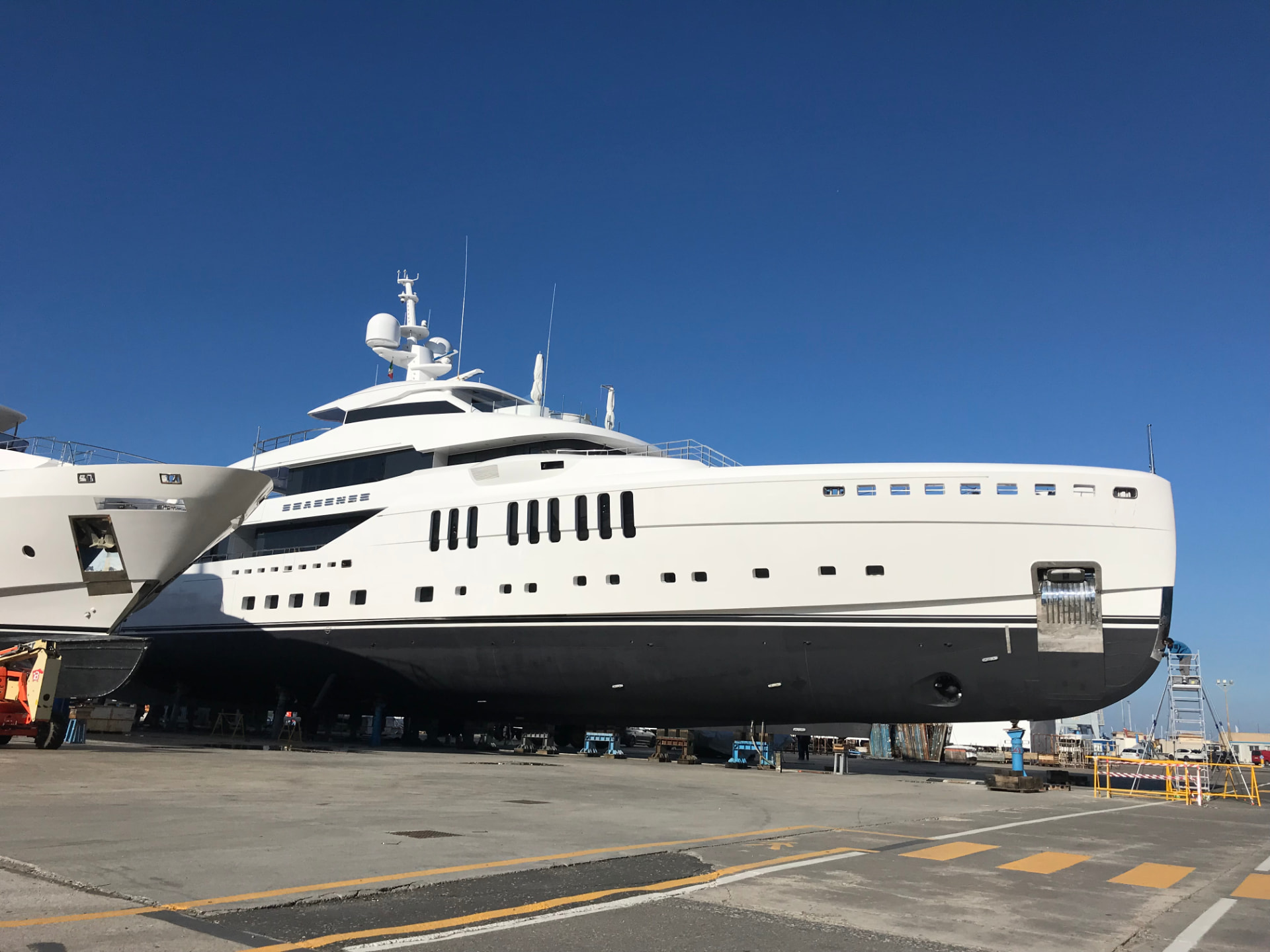 A large white motor yacht standing in dry dock, seen from the side.